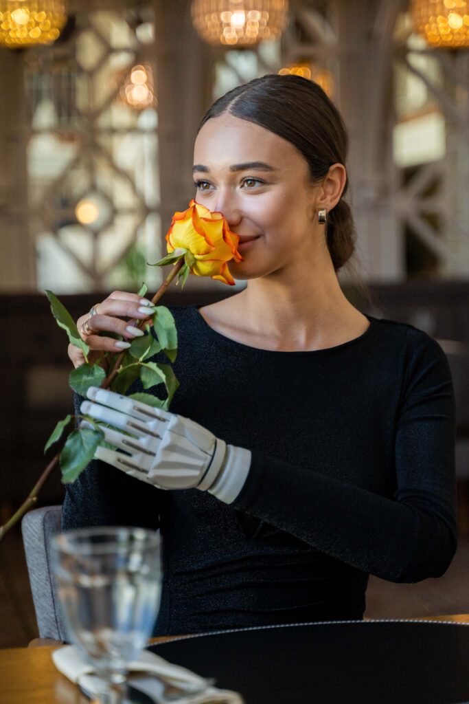Kvinna med robothand luktar på en ros. Våra tjänster inom Ai-optimering och GEO.
